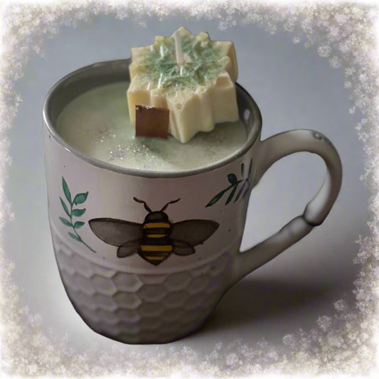 Bee and Snowflake Candle featuring soy wax in a white stoneware bee-themed mug, topped with a snowflake mini-candle, crackling wood wick, and scented with Christmas wreath and mistletoe, displayed on a soft background.