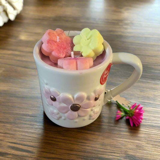 white mug with pink daisies, hand poured soy wax candle inside with 3 flower-shaped wax melts on top