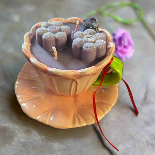 Petals & Serenity Candle Set with lavender-purple soy wax candle in a pink flower-shaped stoneware teacup and saucer, green leaf-shaped handle, delicate flower wax melt accents, displayed on a charming pink flower saucer